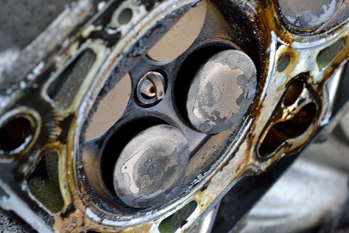 A cylinder head removed from an engine, with several intake valves visibly bent out of line after a timing belt failure allowed the pistons to strike them