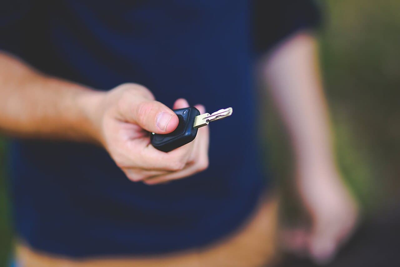 A seller holding out a car key on handover day