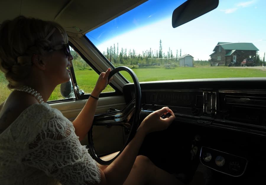 A woman driving her vintage car on a sunny day
