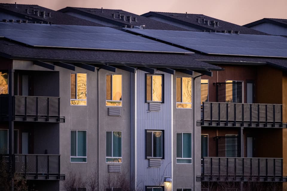 Rooftop solar panels on a modern house under a clear sky.