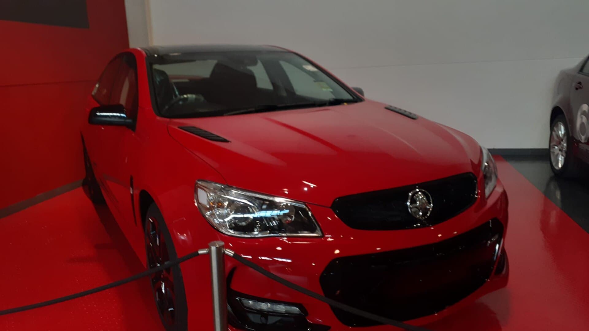 A dark Holden Commodore SS V Redline sedan displayed indoors at a motor museum.