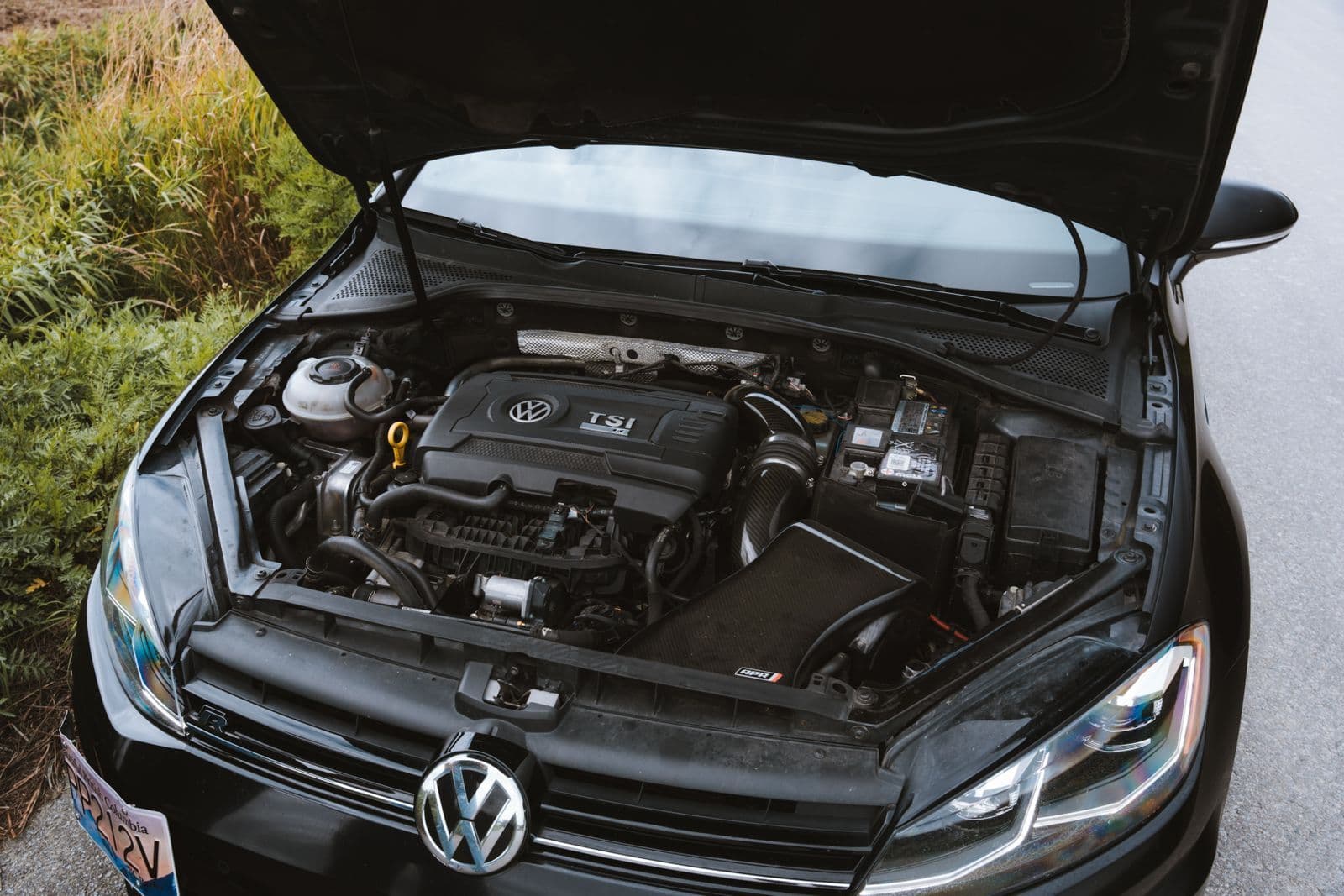 The open bonnet of a black hatchback showing its turbocharged four-cylinder petrol engine.