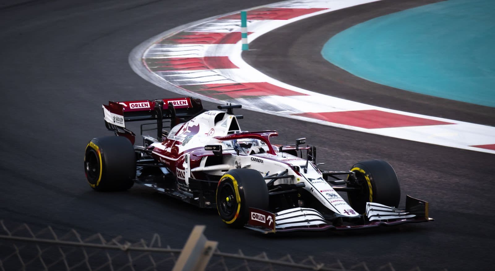 A red and white Formula One car cornering past a painted kerb on a racetrack.