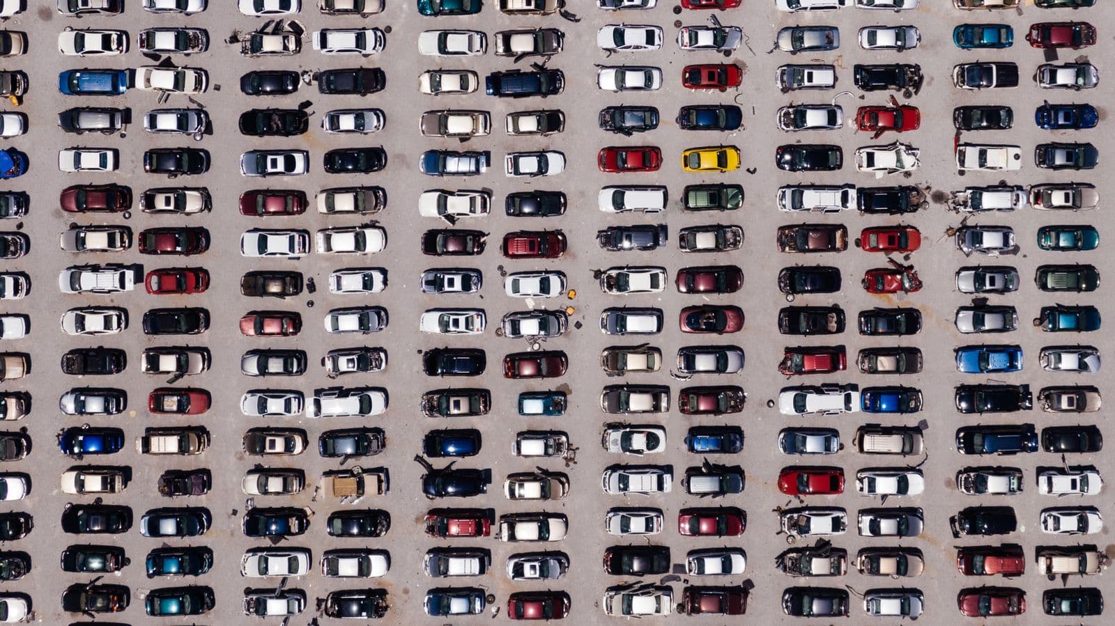 A top-down aerial view of a huge car park packed with rows of cars in many colours.