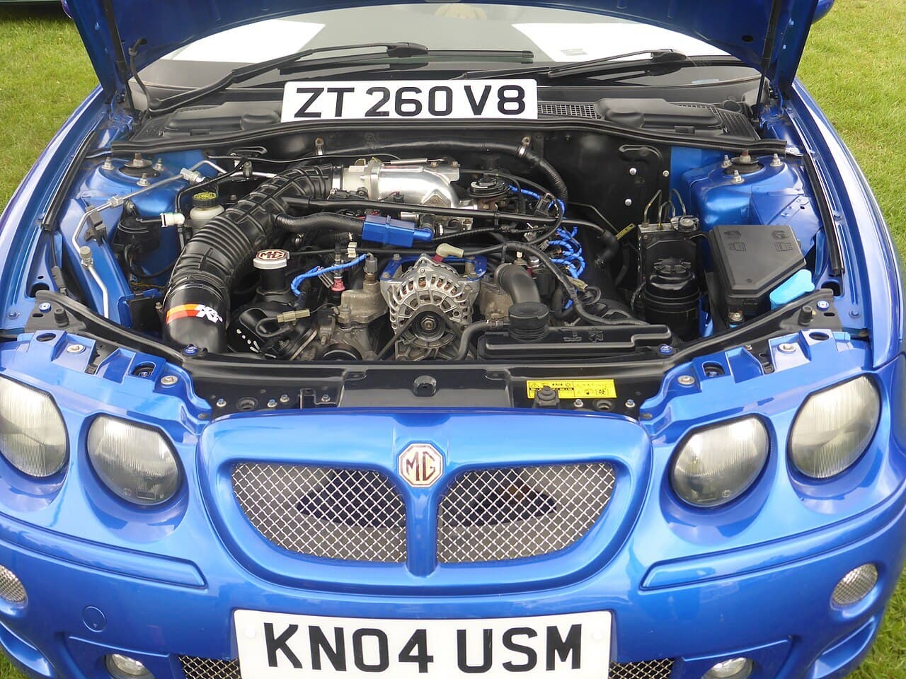 A dark MG ZT 260 V8 sedan parked on grass at an outdoor classic car show.