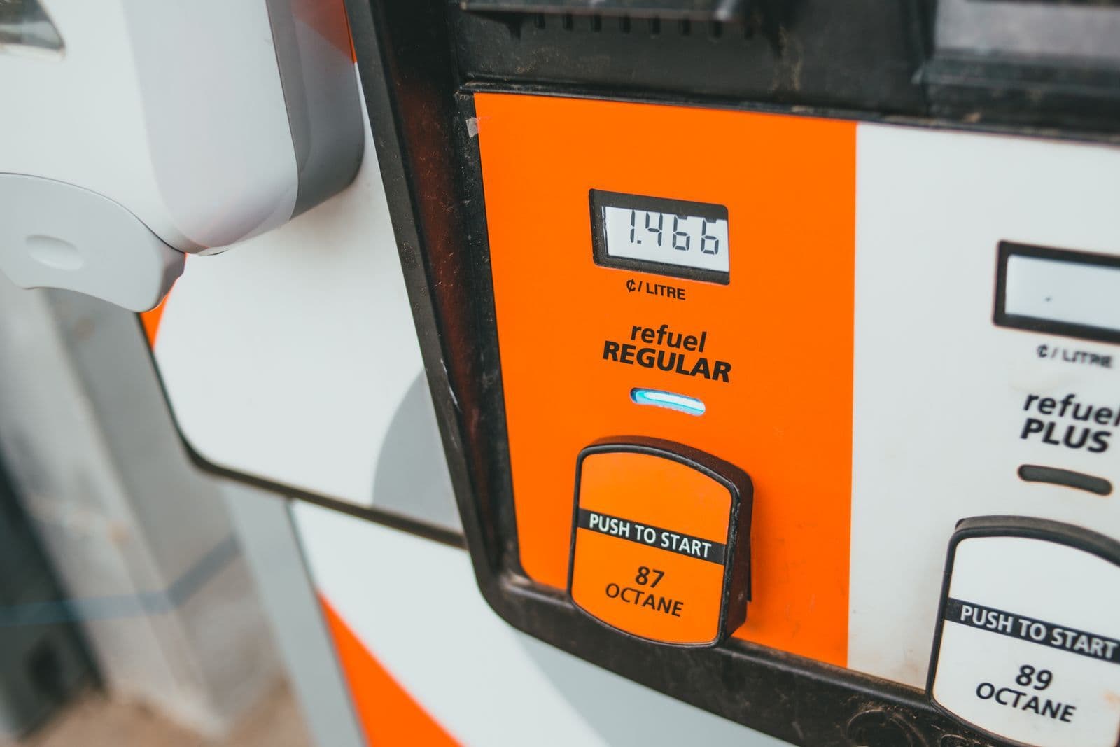 Close-up of an orange and white fuel pump face showing a price of 146.6 cents per litre above a push-to-start button.