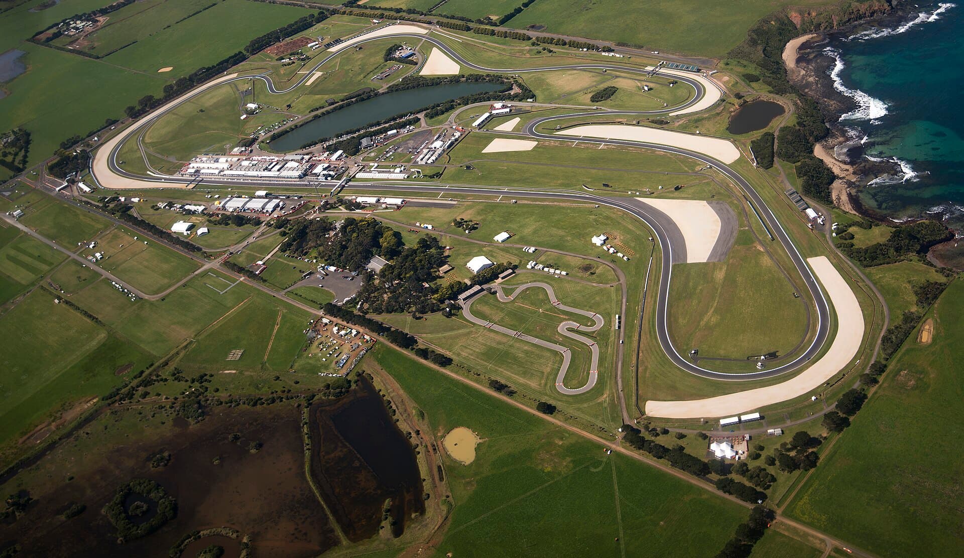 An aerial view of the Phillip Island Grand Prix Circuit and surrounding farmland near the coast.