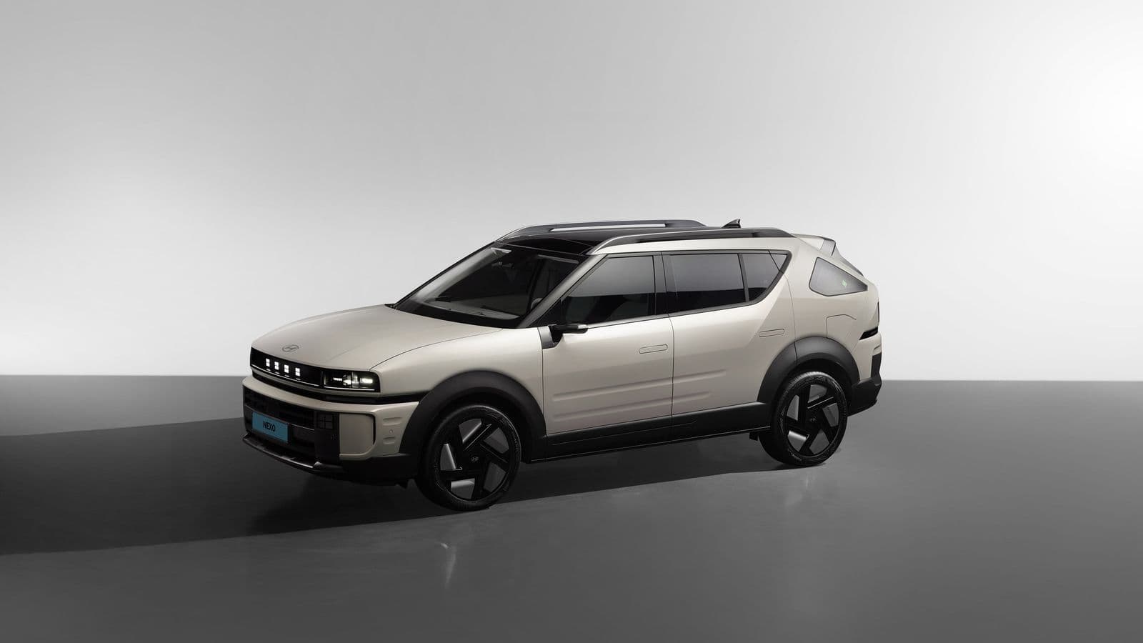 A pale beige Hyundai Nexo fuel-cell SUV photographed in three-quarter view against a plain grey studio backdrop.