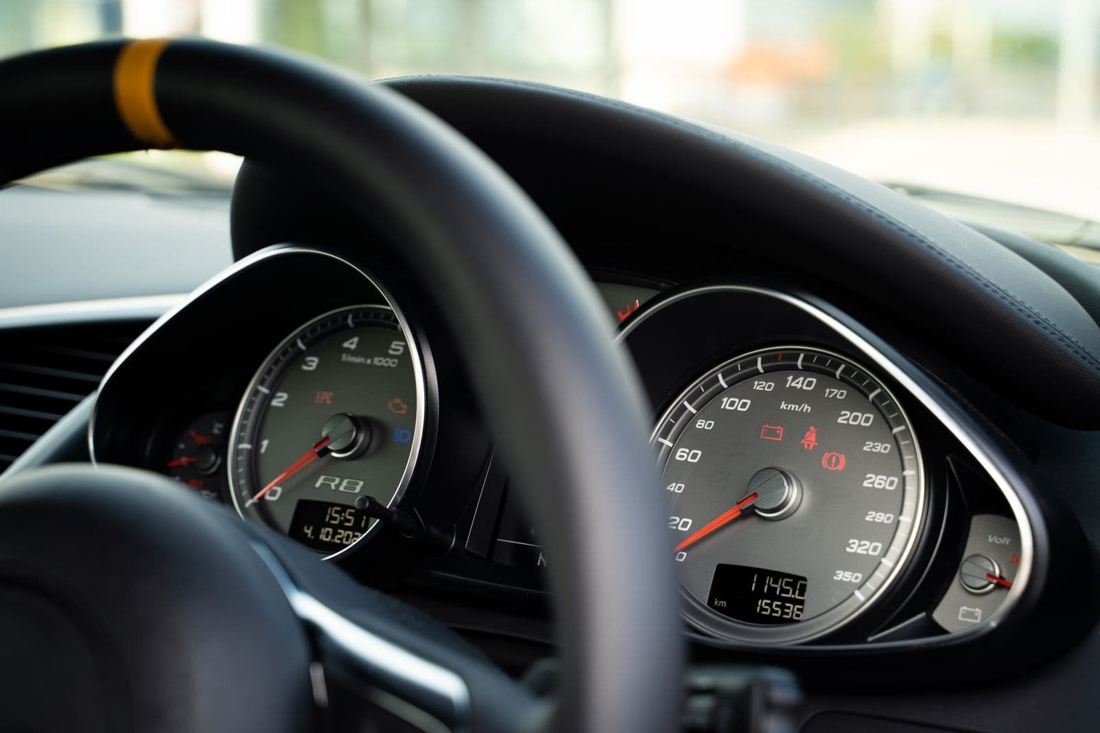 A car's instrument cluster seen through the steering wheel, with the odometer reading just over fifteen thousand kilometres.