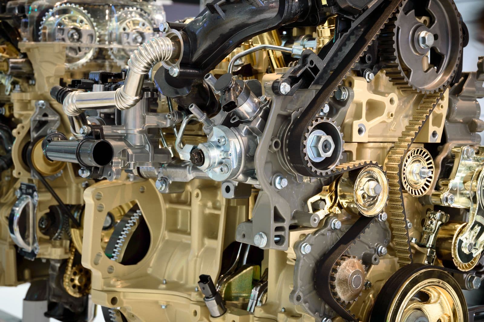 A close-up of a cutaway engine showing its toothed drive belt, pulleys, gears and pipework.