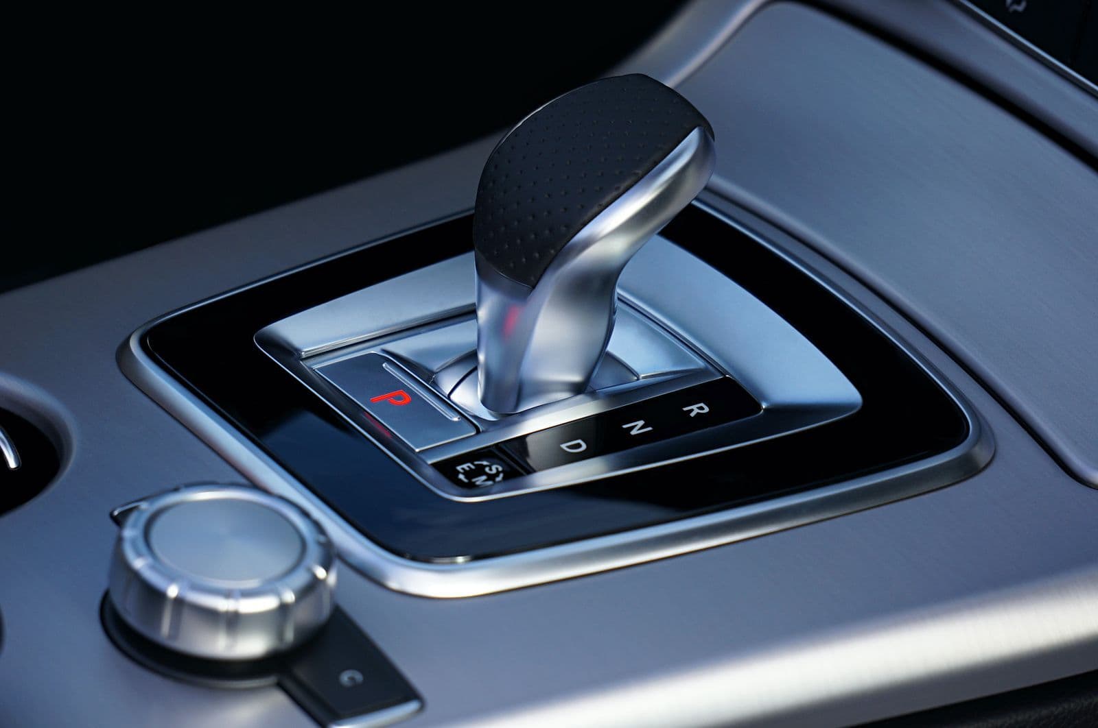 Close-up of a chrome and leather automatic gear selector set in Park, with the P, R, N and D positions marked beside it.