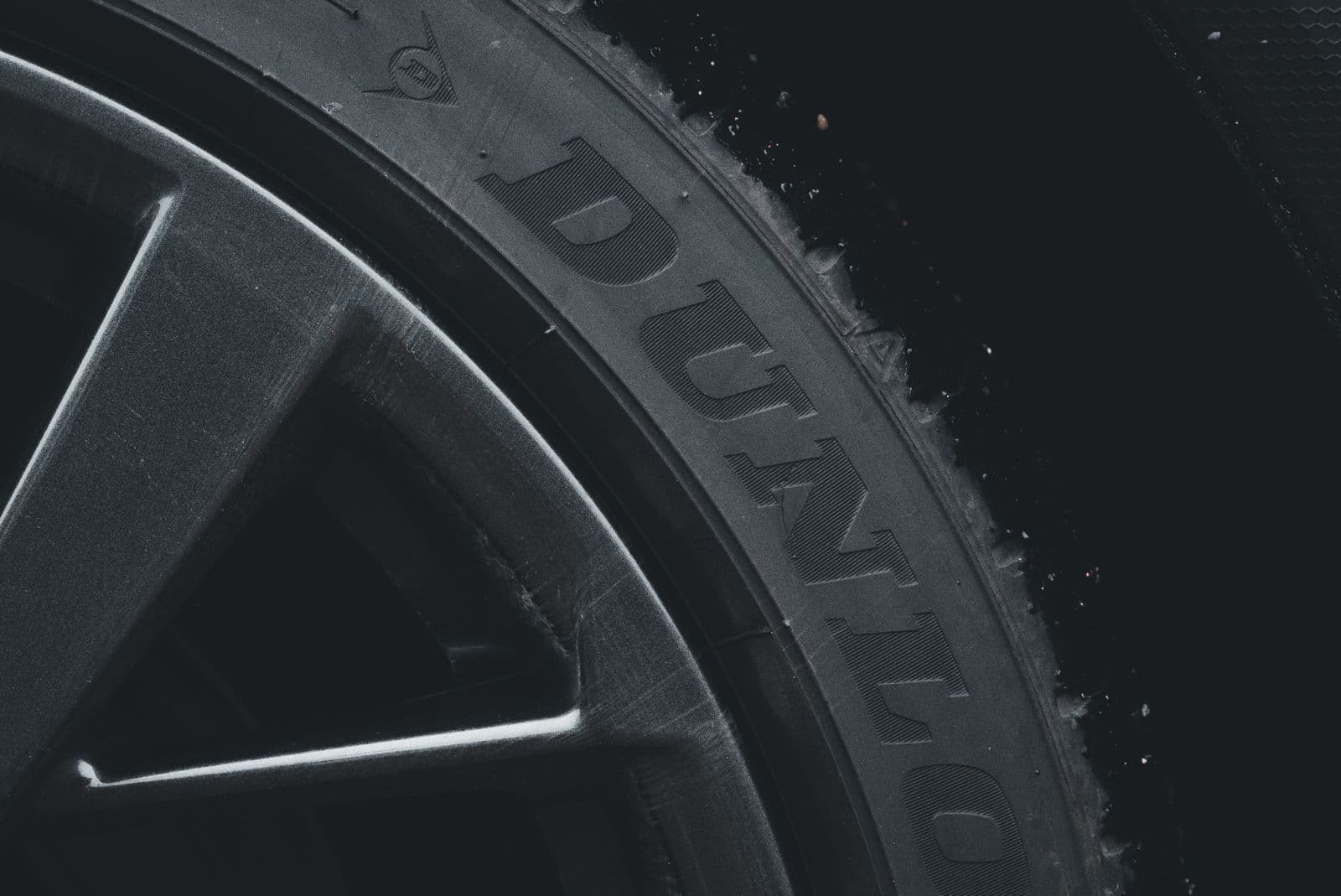 A close-up of a car tyre sidewall showing the raised moulded lettering beside an alloy wheel spoke.