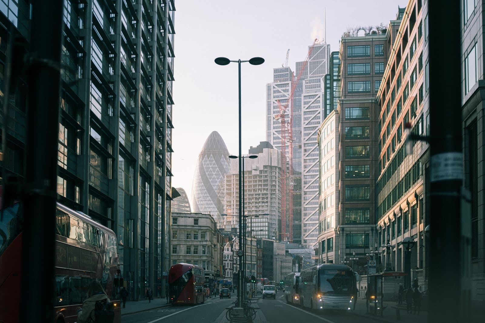 Red double-decker buses and cars on a city street lined with glass office towers.