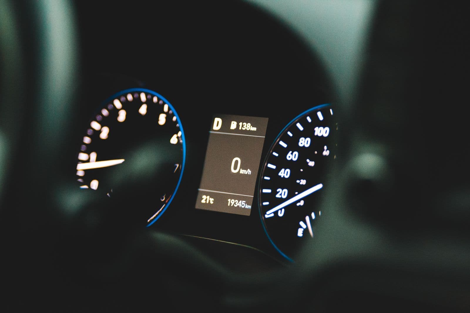 A car's illuminated instrument cluster in a darkened cabin, the centre screen reading 0 km/h and an odometer of 19,345 km.