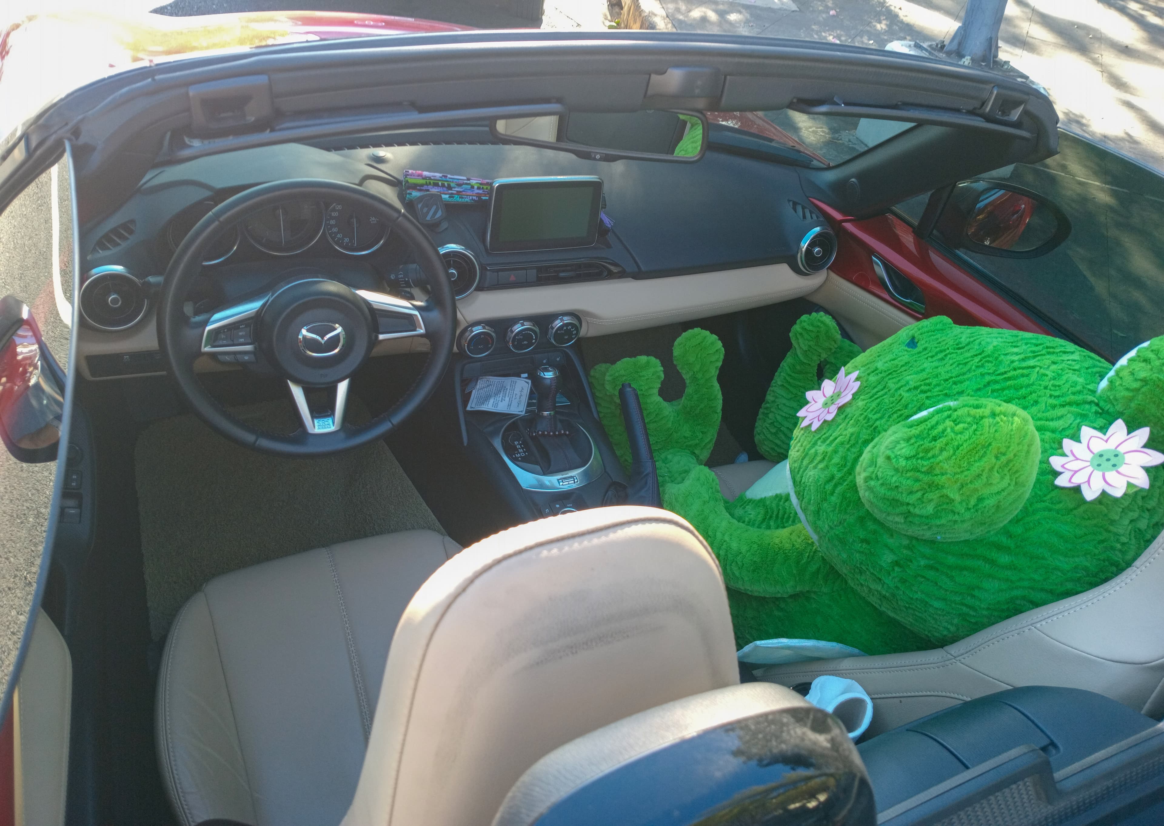 The dashboard of a Mazda MX-5, with a small screen set above three round climate-control knobs on the centre console