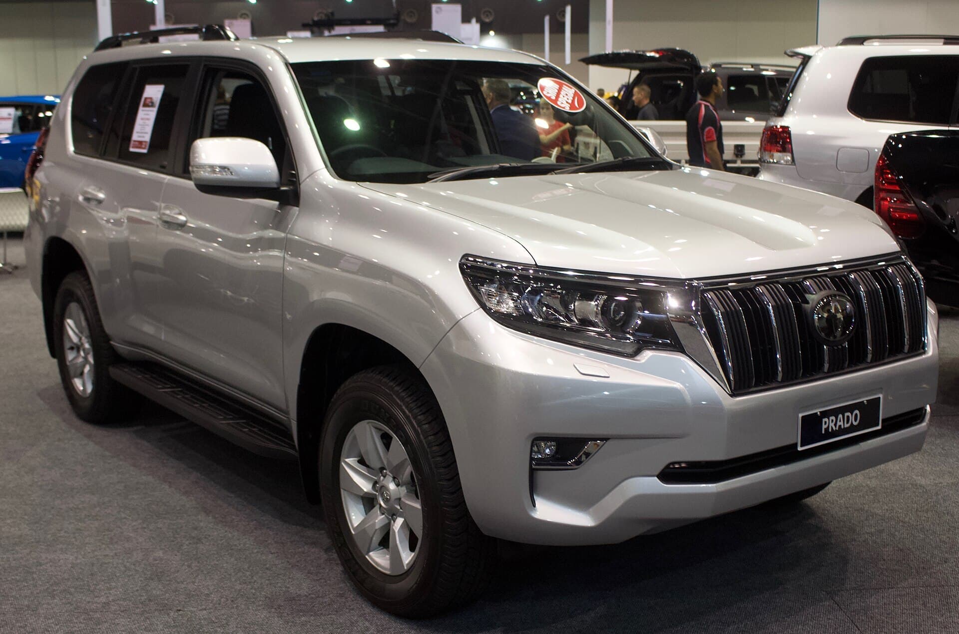 A silver Toyota Land Cruiser Prado wagon on display at an indoor motor show.