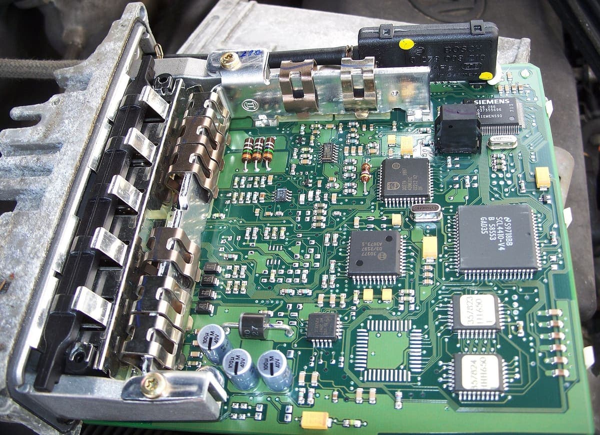 The opened case of a diesel engine control unit, showing the circuit board, connector pins and soldered components inside