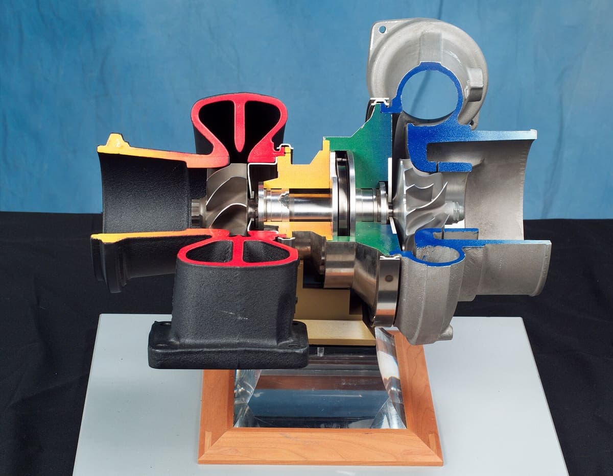 A turbocharger with the housing opened, showing the compressor wheel and the exhaust-driven turbine wheel either side of the central bearing housing that engine oil feeds