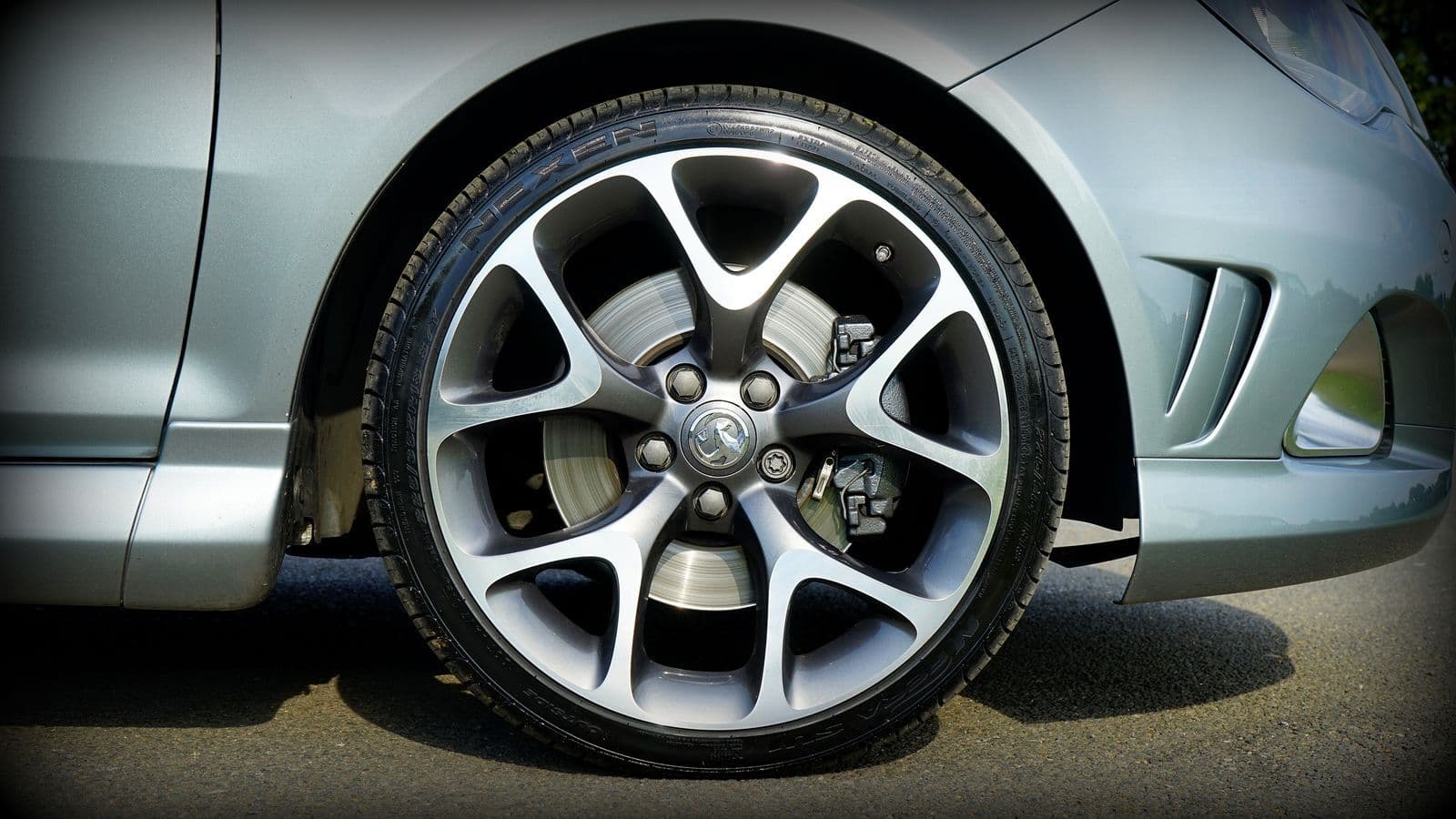 Close-up of a large multi-spoke alloy wheel and low-profile tyre on the front of a silver hatchback.