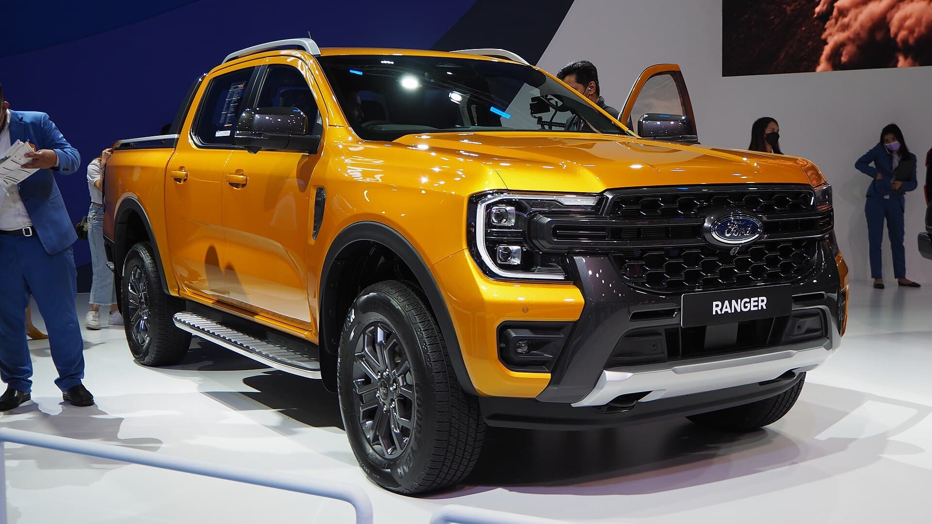 An orange Ford Ranger Wildtrak double-cab ute on display at a motor show.