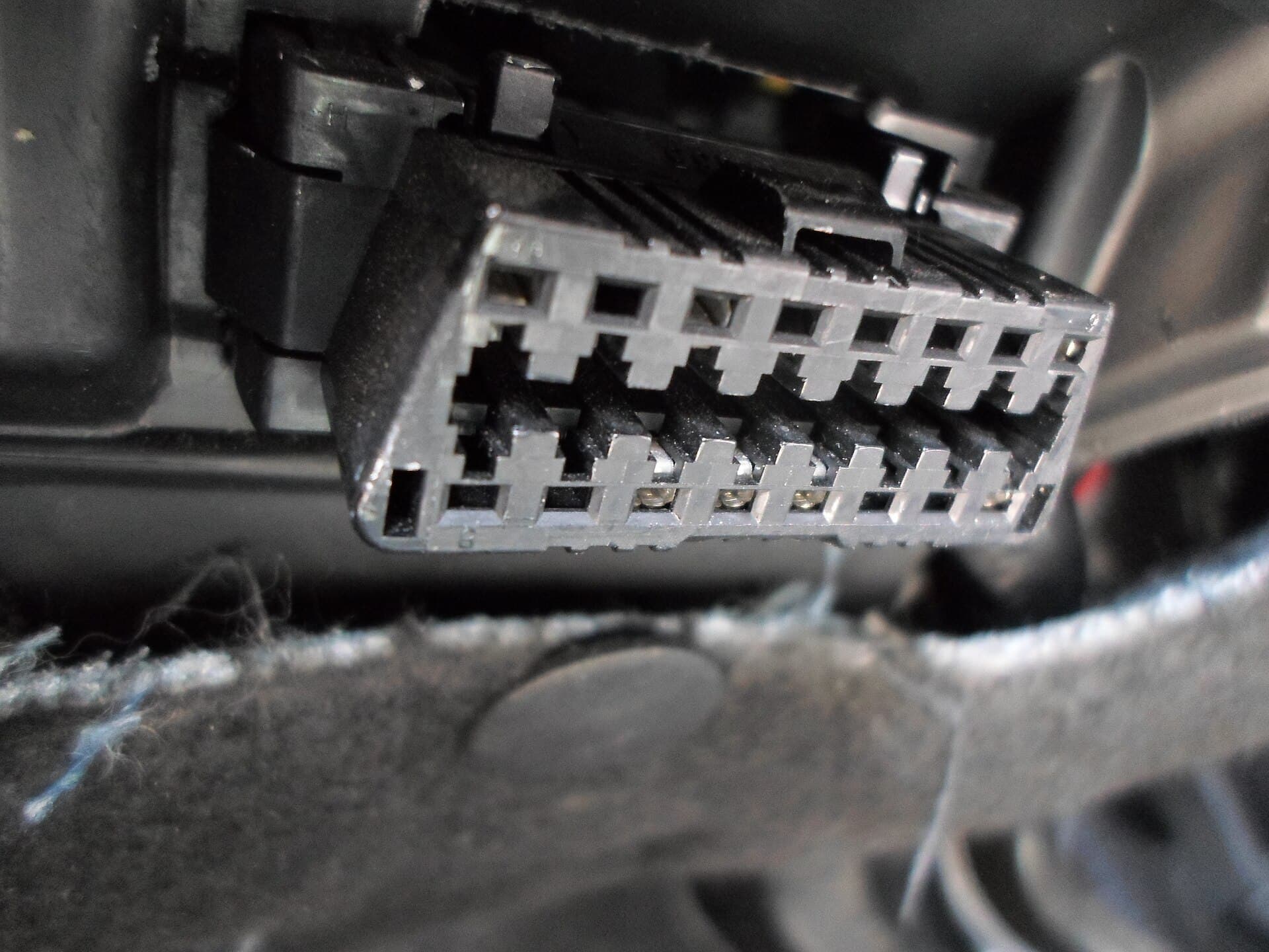 Close-up of an OBD-II diagnostic connector, the port in a car's cabin that diagnostic tools plug into.