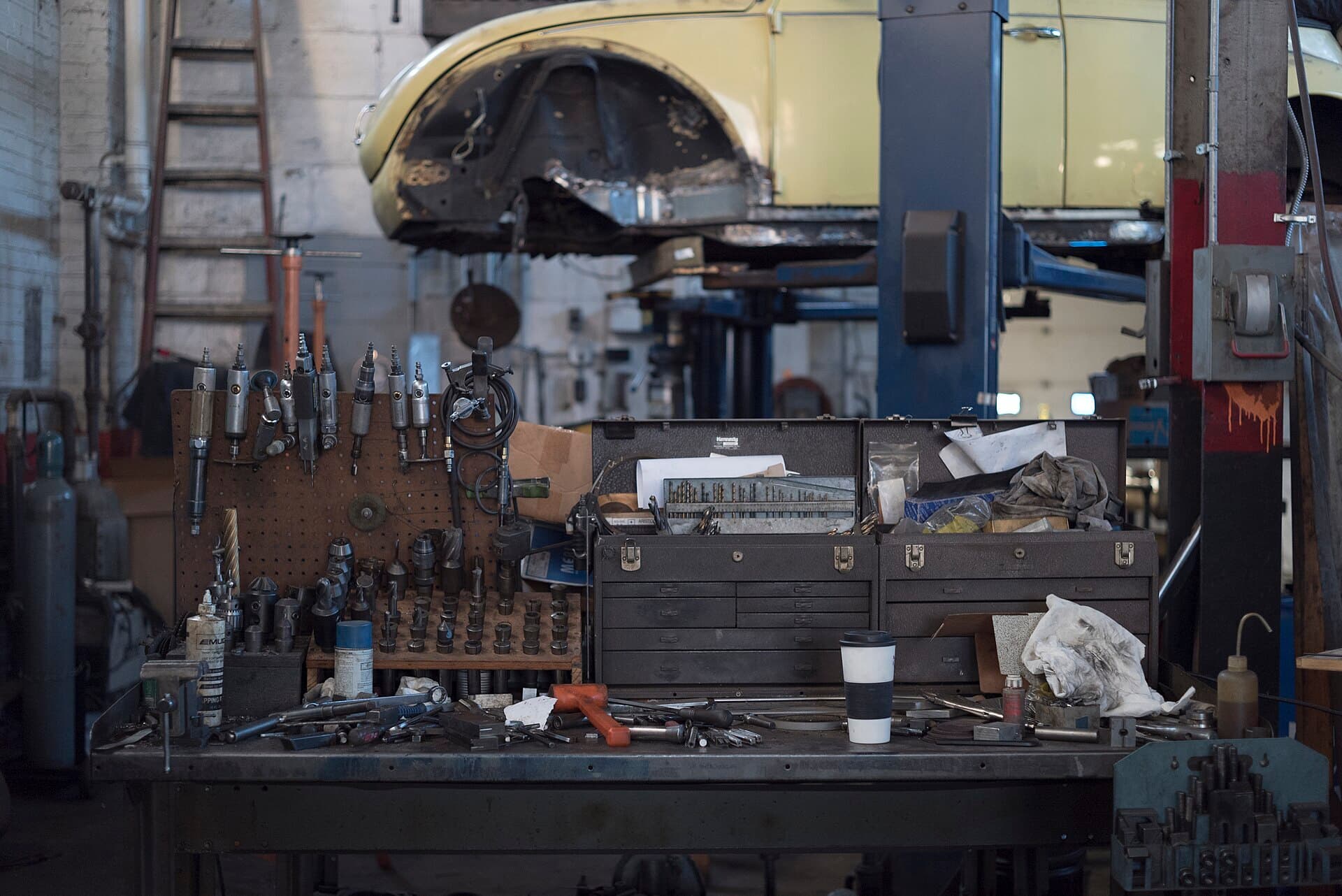 A car mechanic's workbench covered in hand tools and parts.