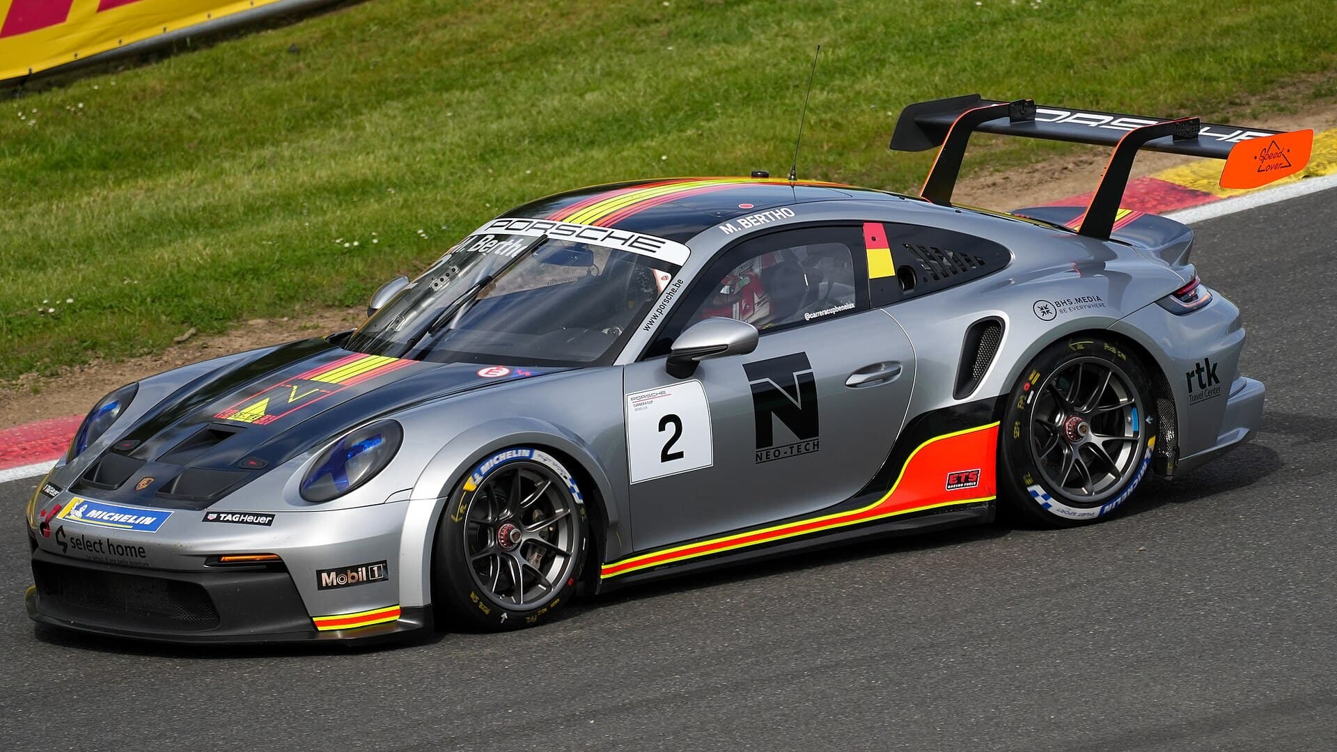 A white Porsche 911 GT3 Cup race car cornering on track during a Carrera Cup race.
