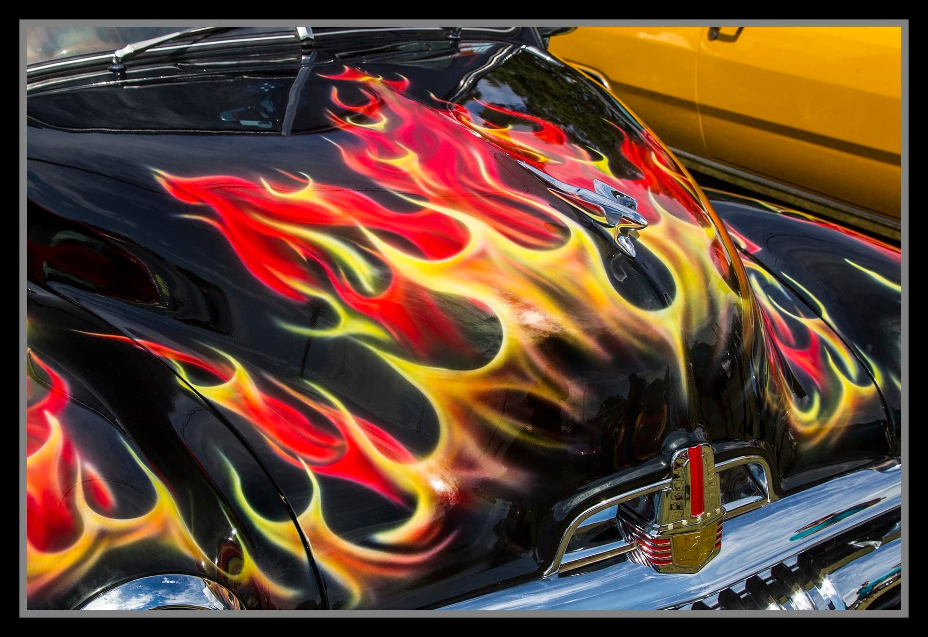 Close-up of a black Holden FJ bonnet painted with red, orange and yellow flames at the Redcliffe car show in Queensland