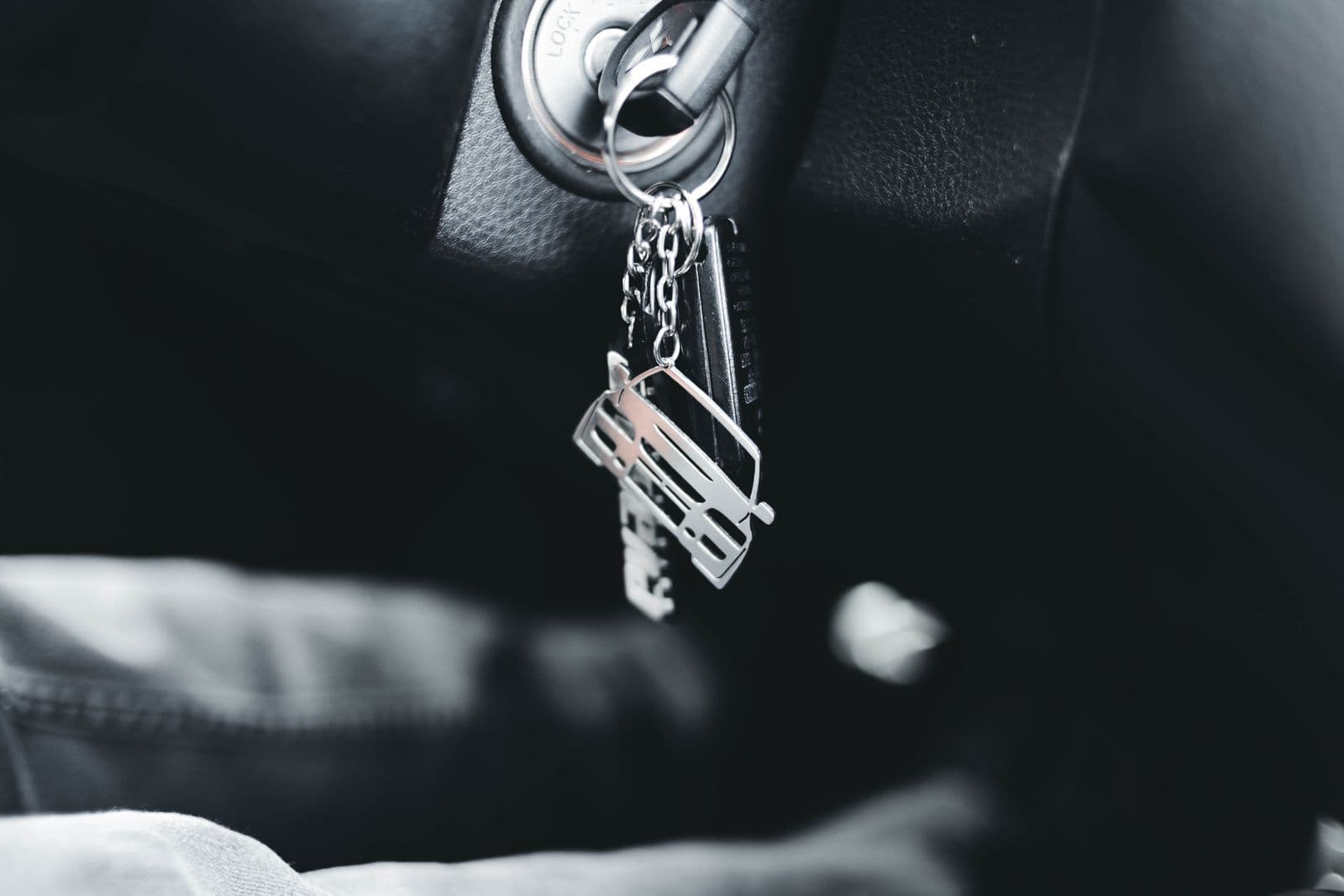 A bunch of keys left hanging in the ignition barrel of a car with a dark interior.